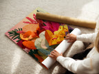 A woman carefully rolls a fine art poster paper. The poster paper features a colorful floral artwork. The woman's delicate handling ensures the artwork's quality is preserved. This high-quality poster paper can be framed or displayed as is. A great art piece.