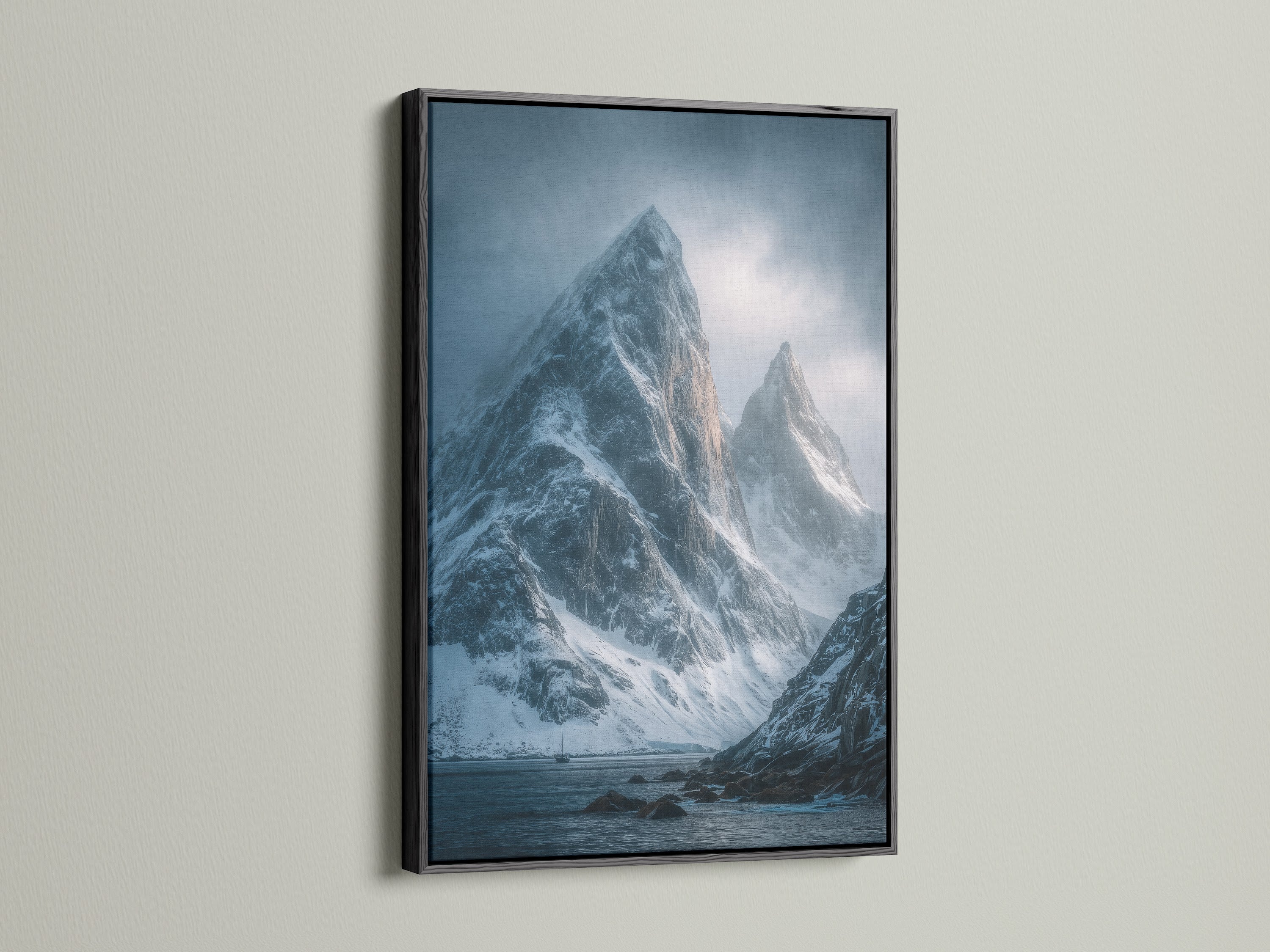 A black frame elegantly presents a scenic canvas of coastal mountain range art. The snow capped peaks create a moody landscape perfect for office wall decor. It's serene winter scenery.