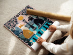 A woman carefully rolls a fine art poster paper featuring a fox and wolf. The whimsical chess art and pink pastel colors make it perfect for kids room decor. This fable artwork is a cute contemporary addition. Ideal for animal art lovers looking for storybook illustrations. Enhance your nursery wall art collection.