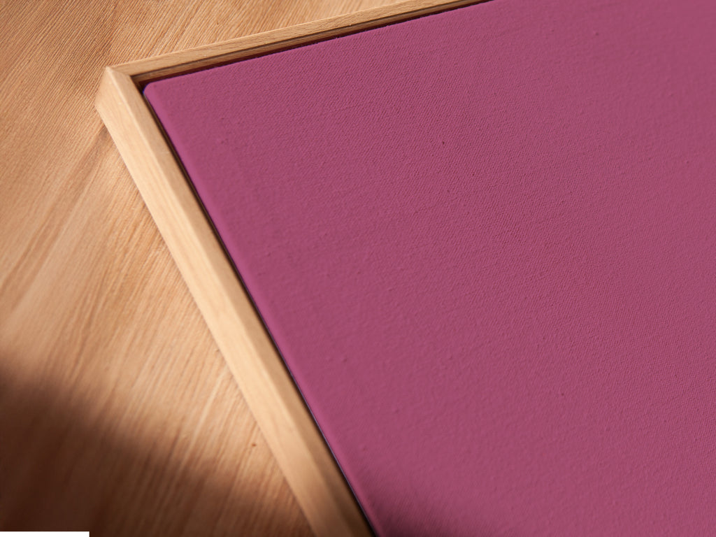 Close-up of a surreal pink artwork. The art features a figure walking away with suitcases. It is displayed in a floating frame. This minimalist canvas print is contemporary. The abstract poster is perfect for office wall art.