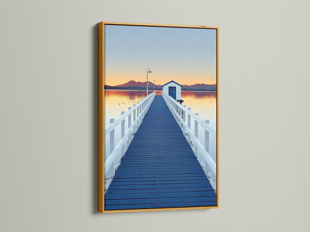 Elevate your space with dock sunset artwork. See a blue pier wall art print in a gold frame. The frame enhances the coastal scenery photography. Bring a touch of nature to your home decor with this piece.