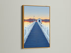 Elevate your space with dock sunset artwork. See a blue pier wall art print in a gold frame. The frame enhances the coastal scenery photography. Bring a touch of nature to your home decor with this piece.