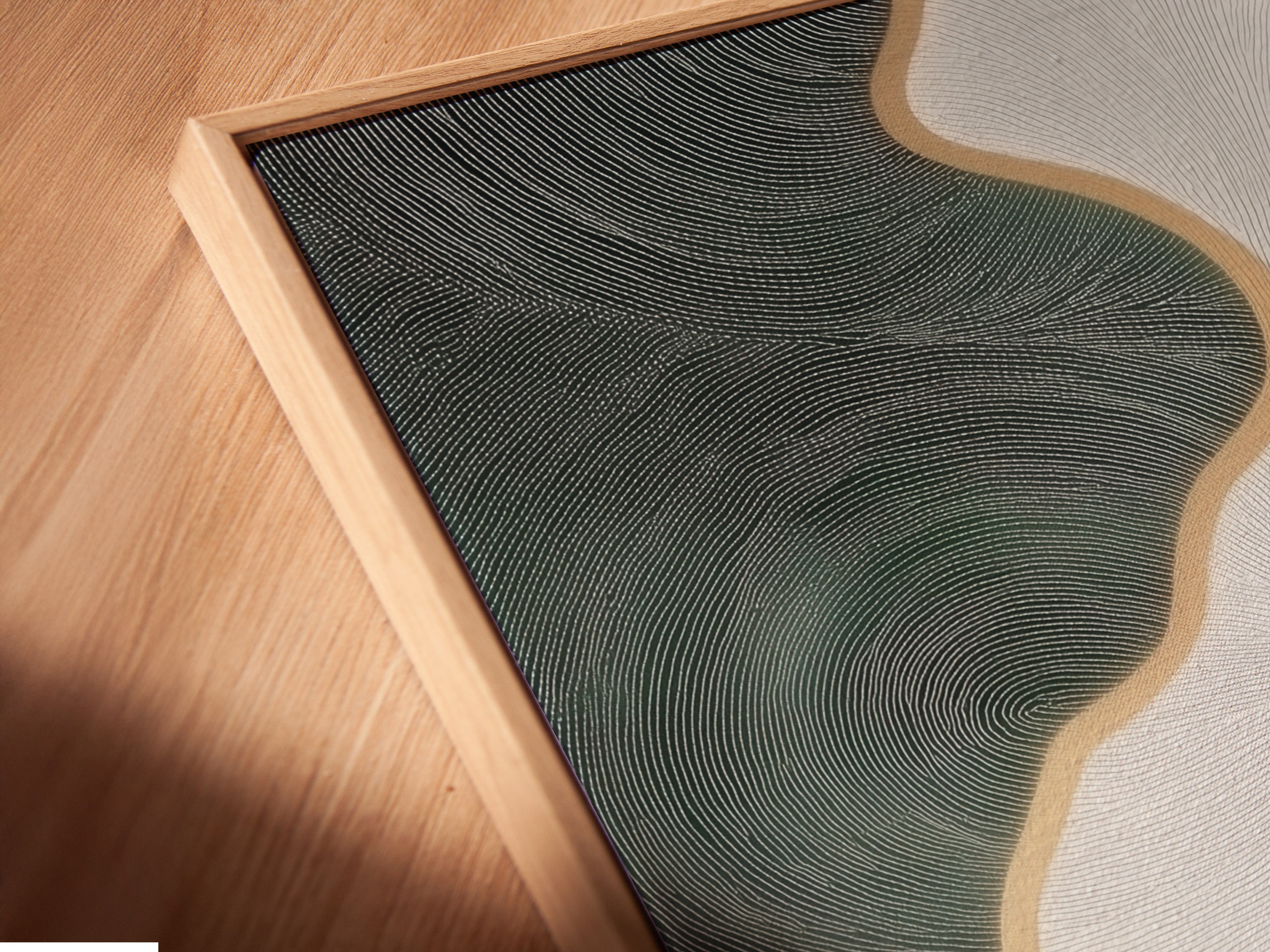 A close-up angle shows a canvas print in a floating frame. The abstract river art features sage green and gold accents. The floating frame enhances the artwork's contemporary feel. This modern print is perfect for adding style to any room. It complements minimalist contemporary or Scandinavian designs. The artwork is ideal for homeowners renters and business owners.