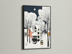 Winter Village art in a black frame hangs against a clean white wall. This winter landscape art complements bohemian and eclectic styles. The snow village print offers a sophisticated seasonal wall art solution.