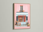 Artwork displayed in an oak frame. The art depicts a quaint bakery with a pink facade and inviting blue accents. The oak frame enhances the artwork's charm. A perfect addition to bring warmth and character to your living space with this piece.