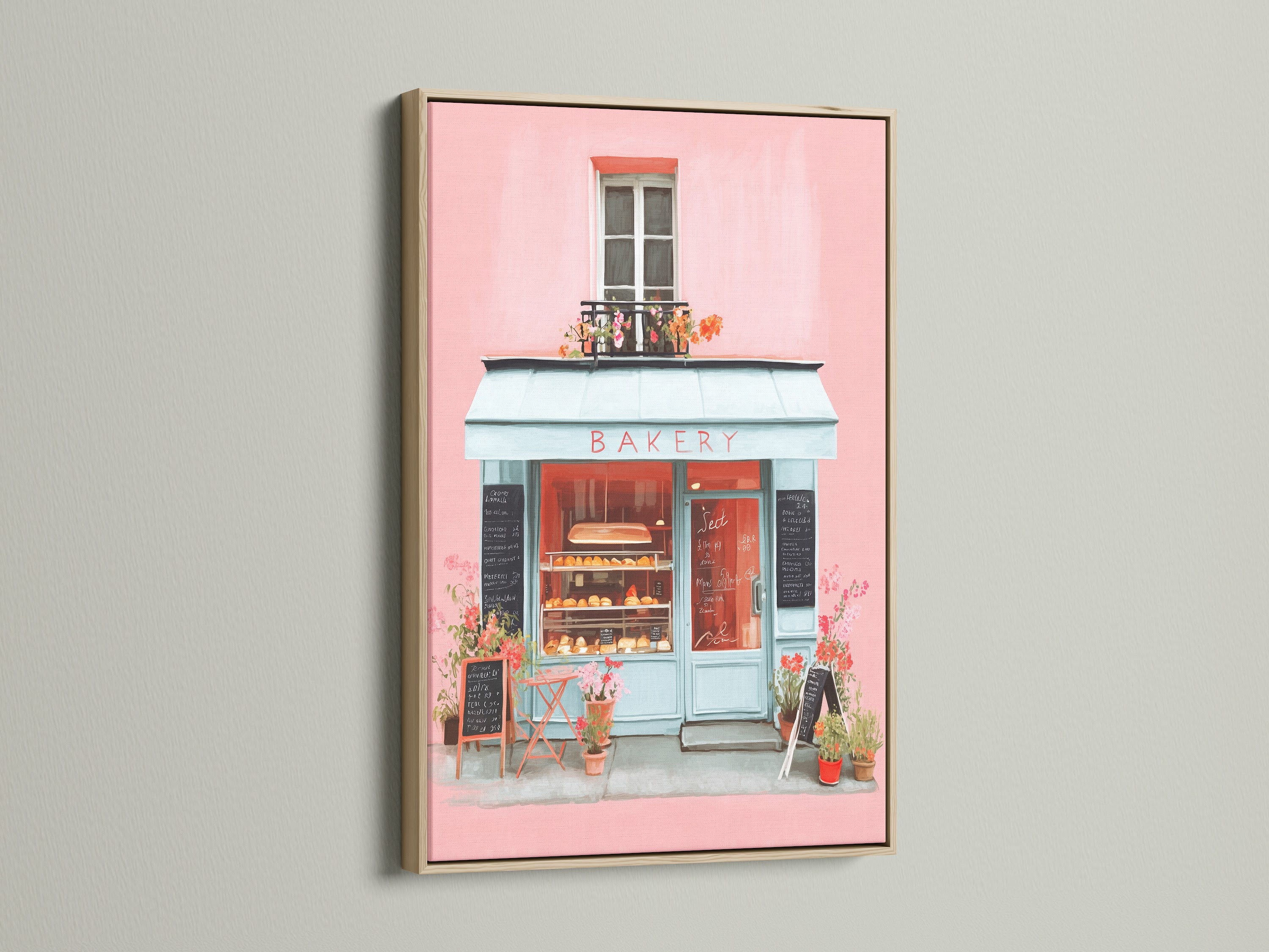 Artwork displayed in an oak frame. The art depicts a quaint bakery with a pink facade and inviting blue accents. The oak frame enhances the artwork's charm. A perfect addition to bring warmth and character to your living space with this piece.
