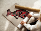 A woman carefully rolls a fine art poster paper. The paper features the Aboriginal Kangaroo artwork. The poster showcases intricate tribal animal art. The red and black details are preserved. This fine art poster is ideal for art collectors.