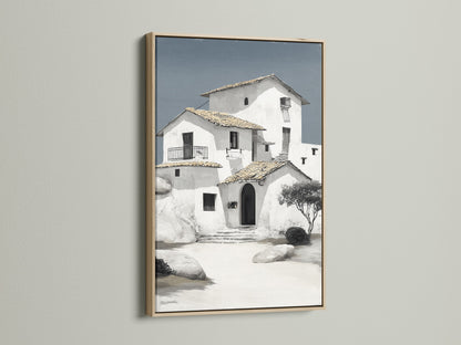 Mediterranean house canvas print with an oak frame on a white wall. This coastal wall art captures a minimalist white building. Perfect for adding a touch of European art to your office wall decor. Shop now and elevate your space with our house artwork.