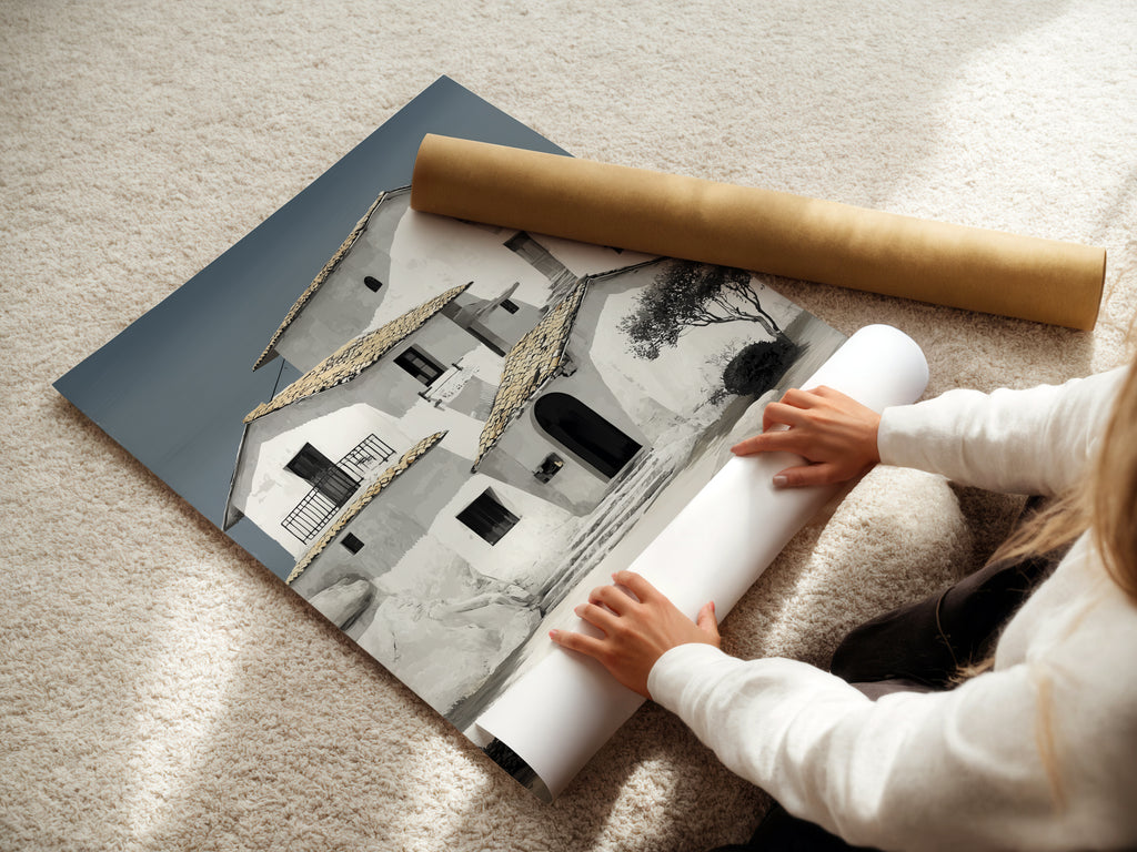 A woman carefully rolls a fine art poster paper featuring Mediterranean house artwork. Perfect for coastal wall art and minimalist decor. Our white building art is ideal for any setting. Explore our collection of architecture prints. Shop now and elevate your space.