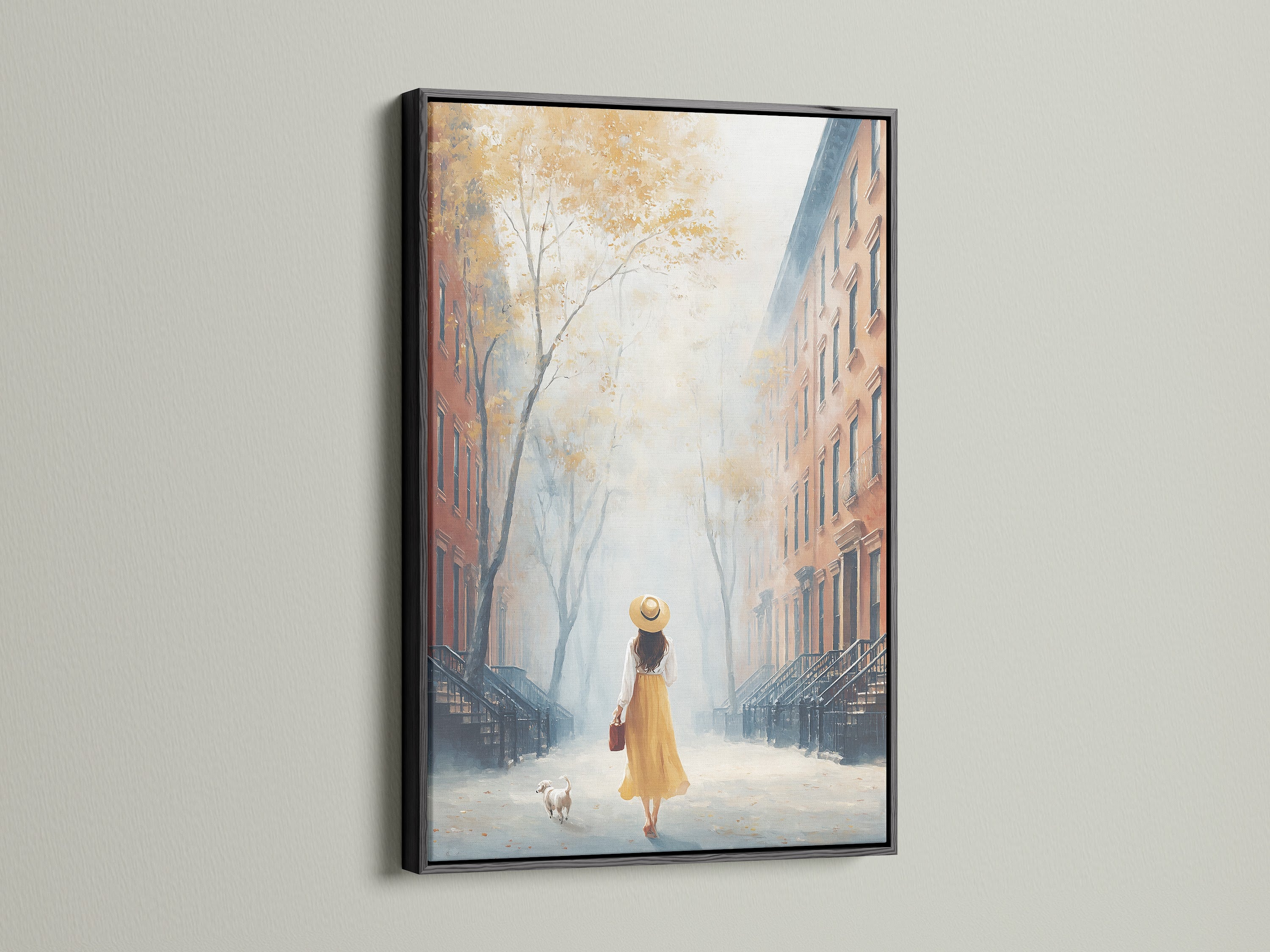 City Street artwork in a black frame. The artwork features a woman and her dog on a townhouse-lined street. The black frame adds a modern touch. This piece would be a great addition to office wall art. The artwork has fall colors.
