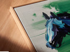 A close-up shows a canvas print in a floating frame. This abstract equestrian artwork features blue green hues. The floating frame adds depth to the horse art print. A refined modern style enhances contemporary spaces.