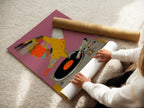 A woman is carefully rolling a fine art poster paper. The paper features the Parrot DJ artwork. This print captures a retro music scene. Perfect for adding funky wall art to your space.