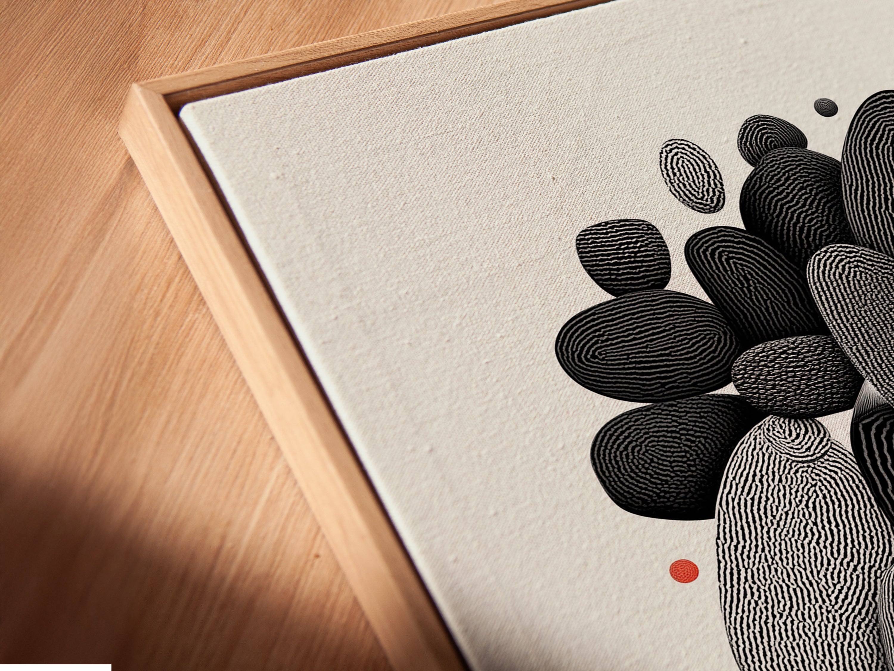 A close-up of a canvas print in a floating frame. The minimalist black and white Abstract Pebble artwork is highlighted. This modern stone art adds a touch of sophistication to any room. Perfect for contemporary and scandi style decor.