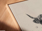 Angled close up of a Highland Cow canvas print in a floating frame. This farmhouse animal art is a stylish addition to any room. The rustic home decor piece is a funny bathroom wall art option. A unique art print.