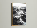 A gold frame displays black and white ocean wave artwork. The metallic finish adds a touch of elegance. Ideal for sophisticated coastal wall art. Perfect for a beach house decor. Browse our wave artwork now.