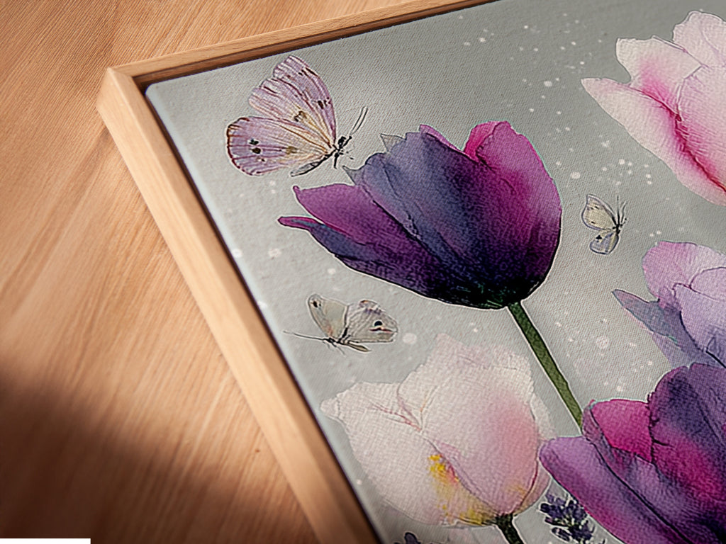 A close-up shot of a canvas print in a floating frame. The artwork features pink and purple tulips. Butterflies add a delicate touch to the floral artwork. The floating frame gives the art a modern sophisticated look. The canvas print is displayed at an angle enhancing its visual appeal.