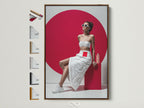 Contemporary fashion artwork in a brown frame. This pop art canvas print features a stylish woman in a white outfit against a red backdrop. Various frame options are displayed. Perfect wall decor for a modern bedroom or fashion retail space.