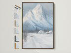 Winter Mountain canvas print in a brown frame is displayed on a white wall. See all frame options to customize your snowy landscape wall art. Perfect farmhouse decor for a cabin. Rustic artwork brings the winter scene to life in any room.