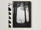 Artwork featuring a black and white image of a solitary figure on a beach framed by trees. The art is displayed in a brown wooden frame. Various frame options are showcased beside it. Explore framing options for your artwork.