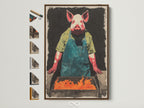 A framed Pig Chef canvas print hangs on a white wall. The artwork features a pig wearing a green apron tending a fiery BBQ. This quirky animal kitchen art adds a humorous touch to any dining room. The brown frame complements the rustic style of the art. Frame options are displayed to the side.