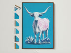 A longhorn cow artwork is displayed in a brown frame. The artwork features a turquoise background. A cow with pink spots stands out. Various frame options are presented on the side. It is perfect for western or farmhouse decor.