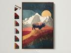 Artwork of a buffalo in a mountain landscape is displayed in a brown frame. This art piece adds a touch of nature to any room. See available frame options on our website. Explore our selection of framed artwork today for your home or office decor. Perfect for adding a touch of wilderness.