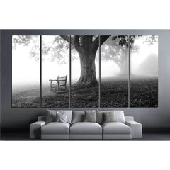 Shenandoah Park Misty Morning Canvas Print - B&W Nature Wall ArtThis canvas print captures a serene monochromatic scene from Shenandoah National Park, depicting a solitary bench under a large tree, enveloped in mist. The image conveys a sense of peaceful